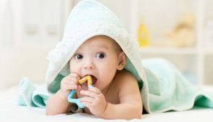 42593610 - baby with teether in mouth under bathing towel at nursery